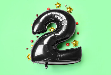 Black balloon in shape of figure 2 and Christmas balls on green background