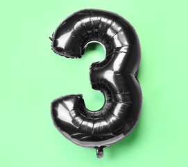 Black balloon in shape of figure 3 on green background