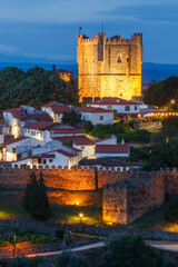 Keep of Bragança Castle in Portugal at dusk with houses from the medieval citadel and walls in the foreground.