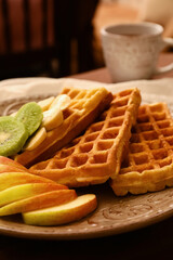 Plate of tasty Belgian Waffles with fruits on table in cafe, closeup