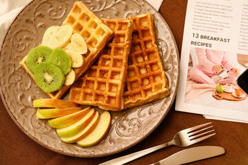 Plate of tasty Belgian Waffles with fruits on table in cafe