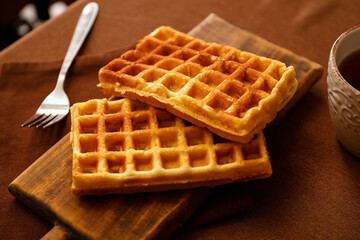 Wooden board of tasty Belgian Waffles on table in cafe