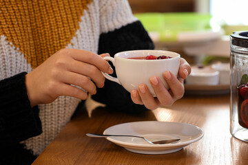 Woman drinking hot tea at table in cafe