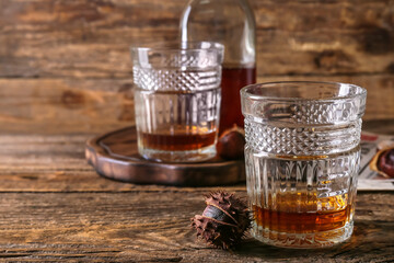 Glasses of chestnut whiskey on wooden background