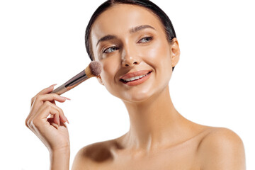 Close up portrait of beautiful woman applying dry cosmetic foundation on face with makeup brush