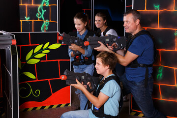 Fototapeta na wymiar Group of happy children and adults with laser guns having fun on lasertag arena