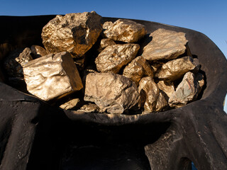 A fragment of a monument to miners mining gold, in the form of a huge iron bucket with gold bars,...