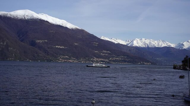 Ferry floats on the lake against the backdrop of snow-capped mountains. Italy, Como