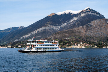 Ferry floats against the backdrop of snow-capped mountains. Lake Como, Italy