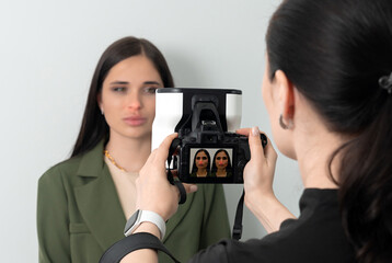 Doctor taking picture of female patient before aesthetic treatment on white background with 3d camera system