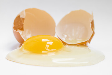 сырое куриное яйцо рядом со скорлупой  на белом фоне, вид сверху