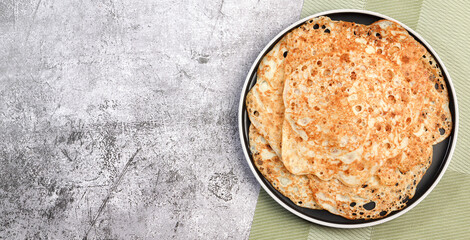 Crepes - traditional russian pancakes on a round plate on a dark background. Top view, flat lay