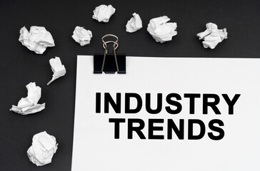 On a black background, there are crumpled pieces of paper and paper with the inscription - INDUSTRY TRENDS