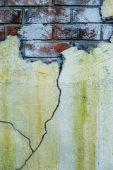 Fragment of an old plastered brick wall with a huge crack, vertical photo