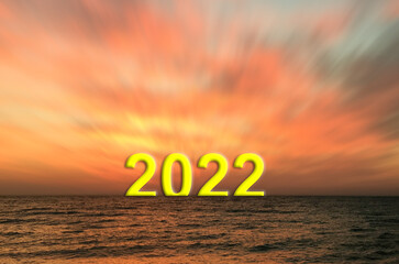 Big 2022 sign rising on the sea horizon at sunset.