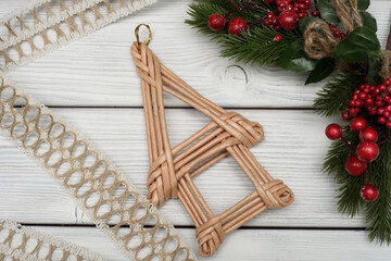 Wicker Christmas decoration. A figure in the shape of a house on a white wooden background.