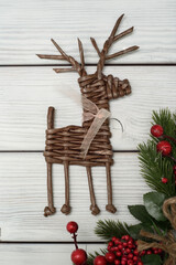 Wicker Christmas decoration on a white wooden background. A figure in the shape of a deer. Handmade work.