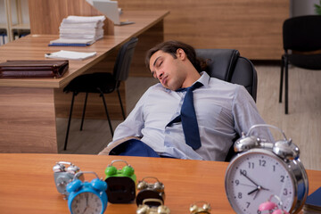Young male employee sleeping in the office in time management co