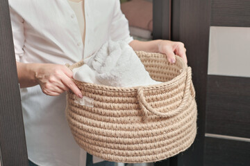 woman holding wicker jute basket with fresh towels in bathroom. zero waste reusable plastic free storage. eco householding concept. partial view.