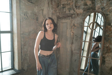 portrait of a young beautiful woman in the studio, in blue jeans near the window