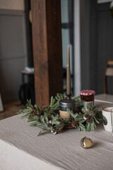 Elegant Scandinavian, nordic hygge style home living room interior with Christmas decorations. Dinner table with linen cloth, candle, fir spruce needles. Christmas dinner celebration preparation