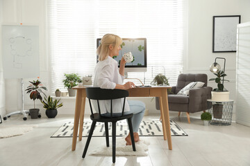 Woman with cup of tea at table in light room. Home office