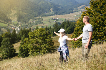 Fototapeta na wymiar Couple enjoying picturesque landscape from top of hill. Space for text
