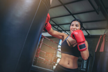 Asian sexy woman doing workout exercise by boxing with sandbag at fitness gym. Selected focus	