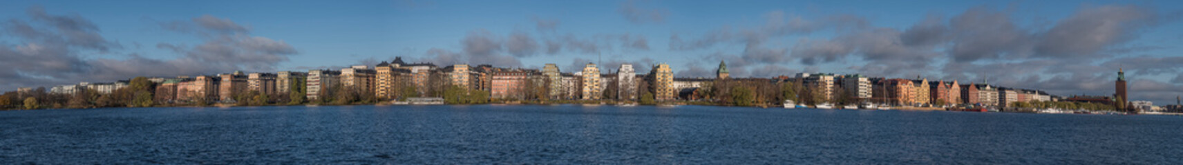 Fototapeta na wymiar Panorama of the water front at Norr Mälarstrand on the island Kungsholmen with the Stockholm Town City Hall a sunny and color full autumn day in Stockholm