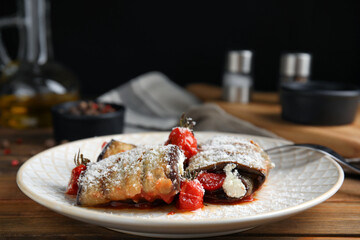 Delicious baked eggplant rolls served on wooden table, closeup