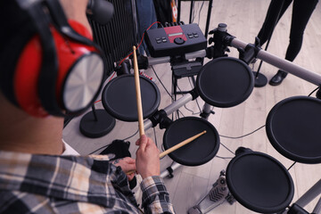 Man playing electronic drum kit during rehearsal in studio, closeup. Music band practice