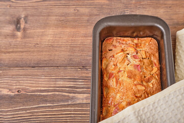 Apple pie in a baking tray on a brown wooden table. Apple charlotte. Homemade apple pie. Close-up, top view