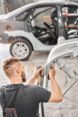 Sanding of car elements. The mechanic works with a grinding tool. Painting car service. Repairing car section after the accident.