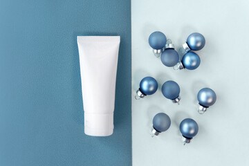 Flat lay top view facial skincare white tube bottle product decorate blue baubles for festive on...