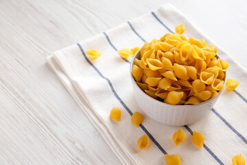 Raw Medium Pasta Shells in a Bowl, side view. Space for text.