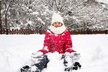 Fototapeta na wymiar Cute little girl playing outside in winter in snowy weather.