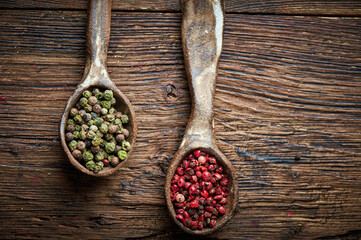 Green and red pepper on an ceramic spoon over wooden backround