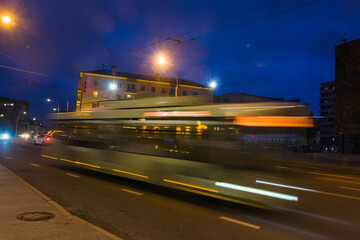 Naklejka na ściany i meble The motion of a blurred bus along the street in the evening.
