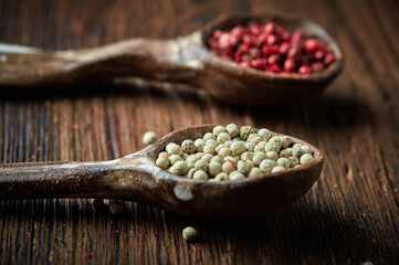 White and red pepper on an ceramic spoon over wooden backround