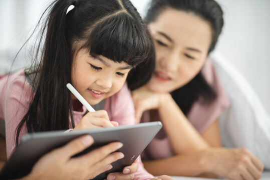 Asian children learning from home, homework learning with father and mother together in daughter family by laptop technology people, happy girl in online education lifestyle