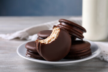 Tasty choco pies and milk on white wooden table