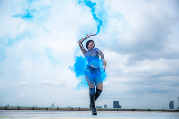 Beautiful young dancer practicing dancing with a blue confetti color waving in the air against a...