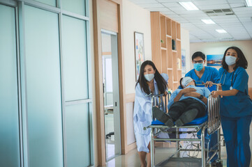 a group of medics or doctors carrying male patient on hospital gurney to emergency or operation room, urgent caseon  gurney being pushed at speed through a hospital.