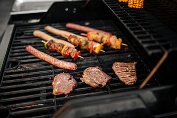 Closeup on grilling sausages and chicken skewers on a barbecue