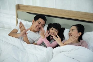 Obraz na płótnie Canvas happy love family lifestyle with Asian father and mother and child daughter at home together