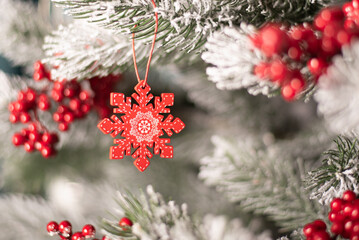 red wooden snowflake figurine on the background of spruce branches. High quality photo. red snowflake on the christmas tree