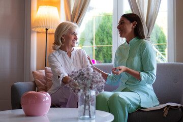 Young female nurse visiting a mature woman at her home, doing a house call visit.