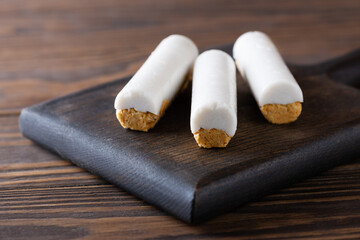 Raw vegan carrot sticks with coconut cream on a dark wooden board. Sugar, gluten and lactose free.