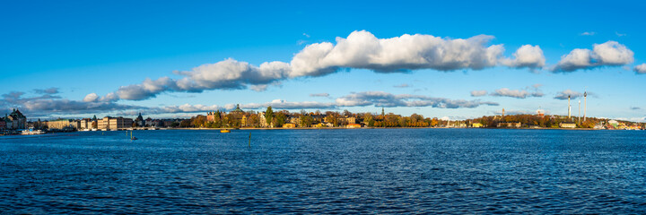 Beautiful autumn panorama of Stockholm, the capital of Sweden on sunny day. The islands of Djurgården and Skeppsholmen. An embankment with old architecture buildings, palaces and attractions park.