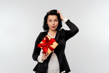 Fototapeta premium Beautiful smiling businesswoman holding gift box decorated with red ribbon. White background isolated studio portrait. Holidays, celebration and lifestyle concept
